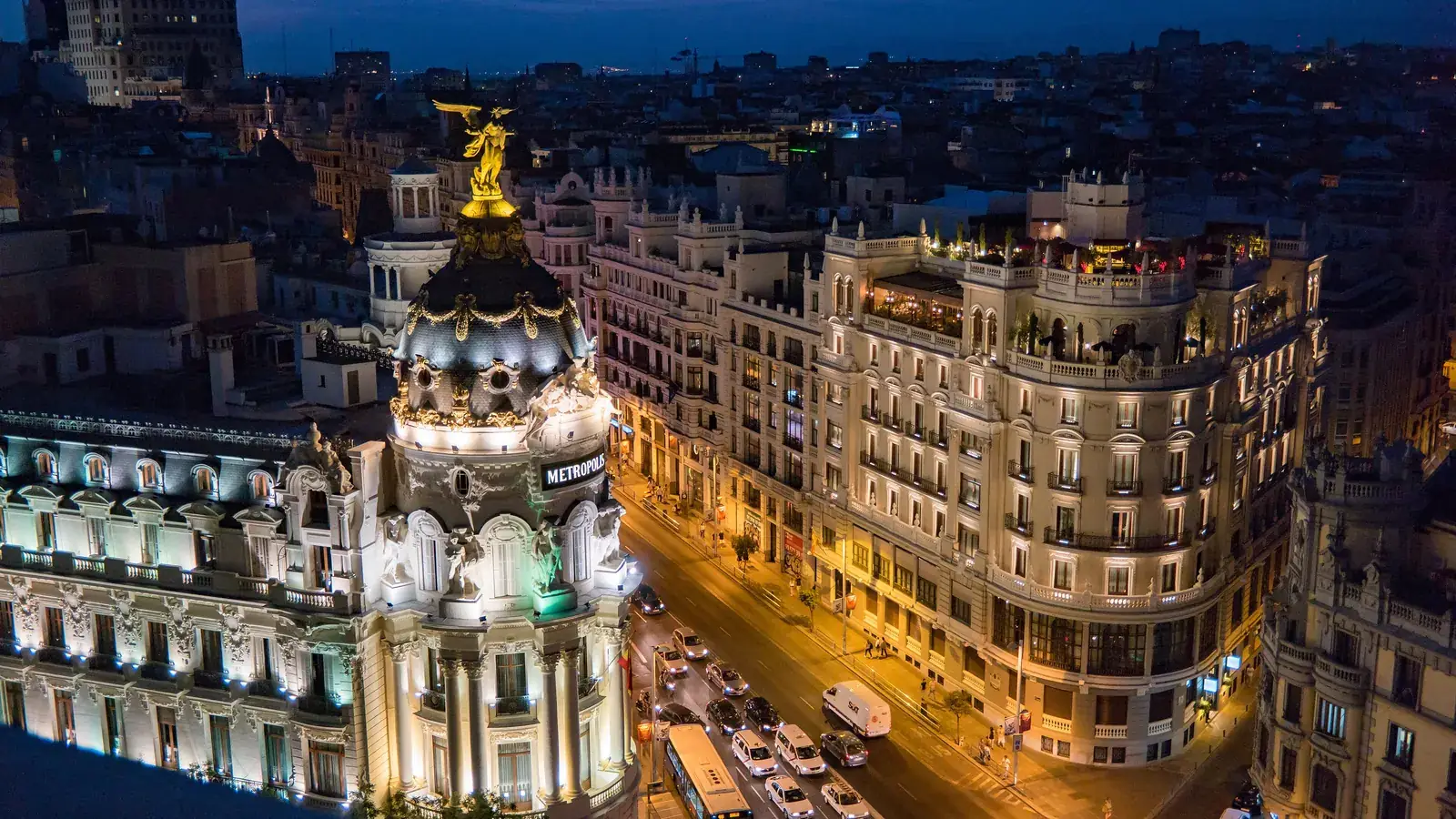 Gran Vía i Madrid i skymningen med Metrópolis-byggnadens kupol
